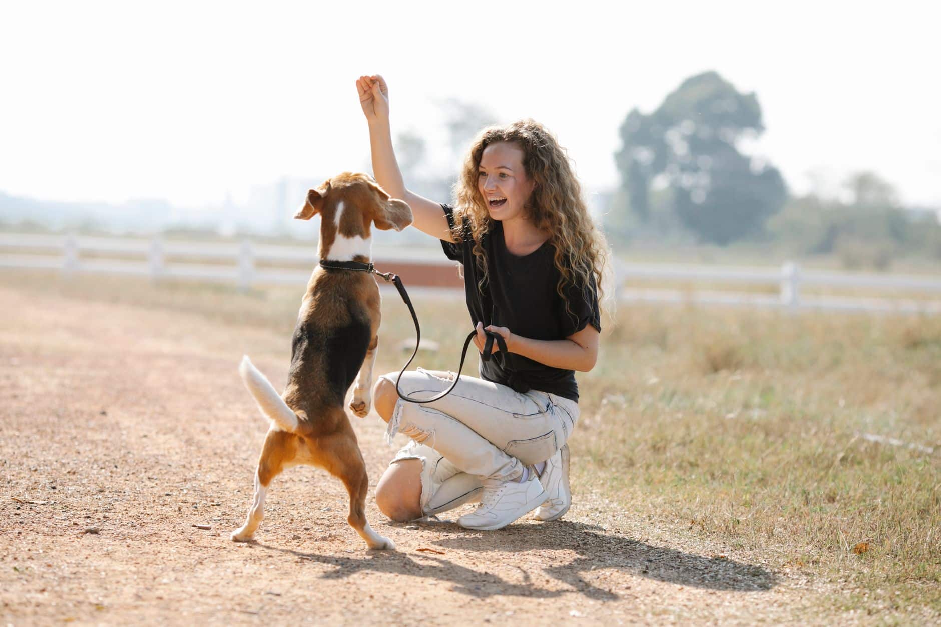 Une éducatrice canine souriante travaille un exercice avec un chien en extérieur